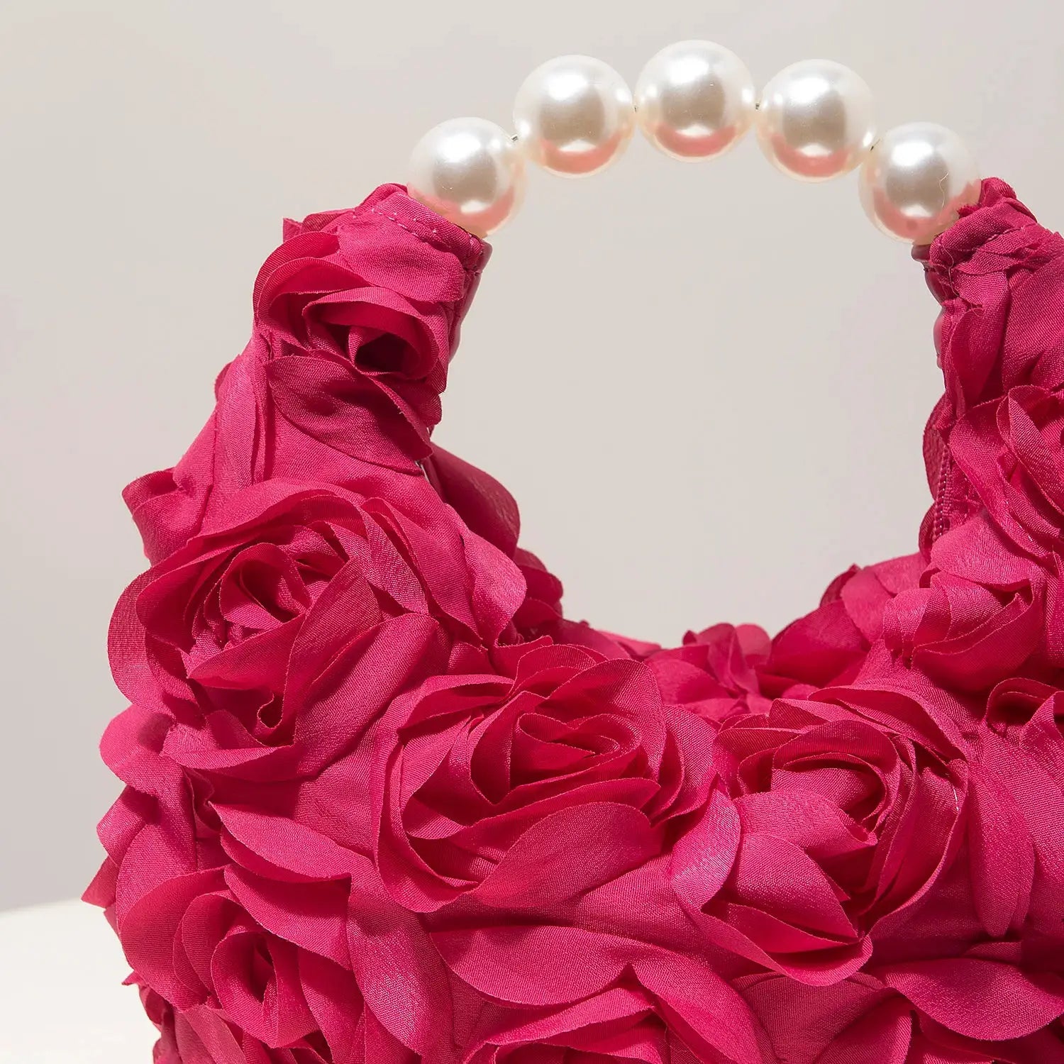 Pink floral rosette clutch handbag with a curved pearl bead handle, ideal for gala, prom, or wedding events