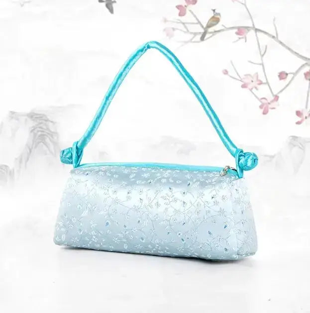 Shoulder bag in light blue satin with delicate floral embroidery and turquoise handle