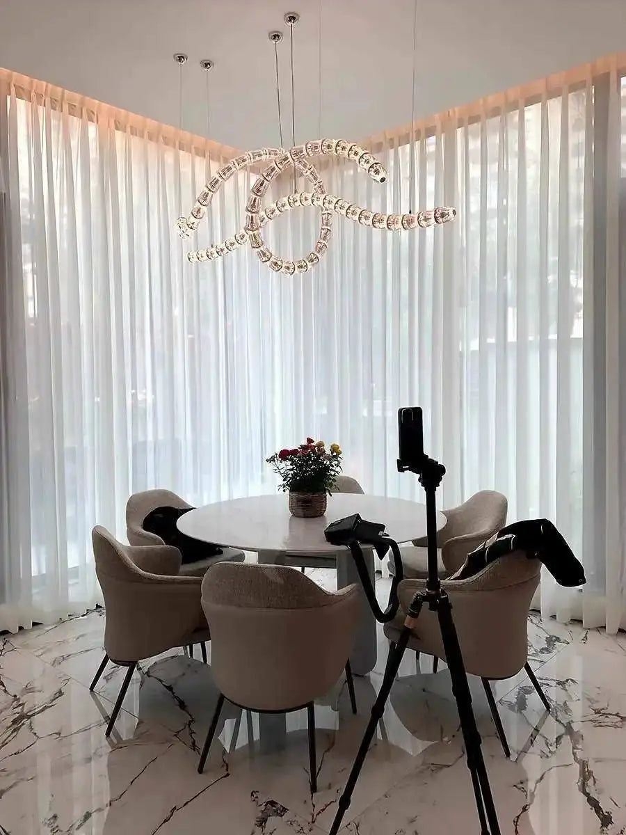 Necklace chandelier with multi-strand crystal acrylic beads, adjustable chain, hanging above a round dining table