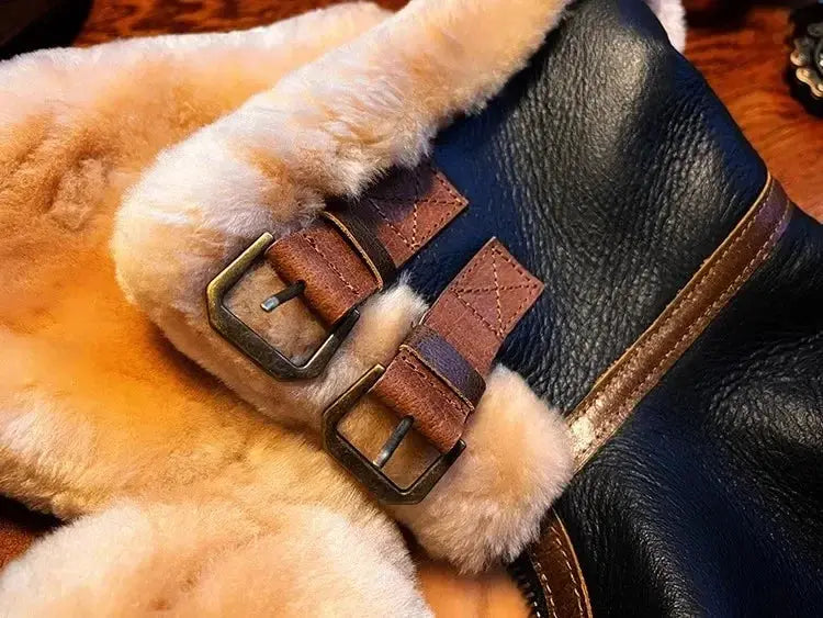 Leather bomber jacket with beige shearling lining, navy body, and brass buckle straps