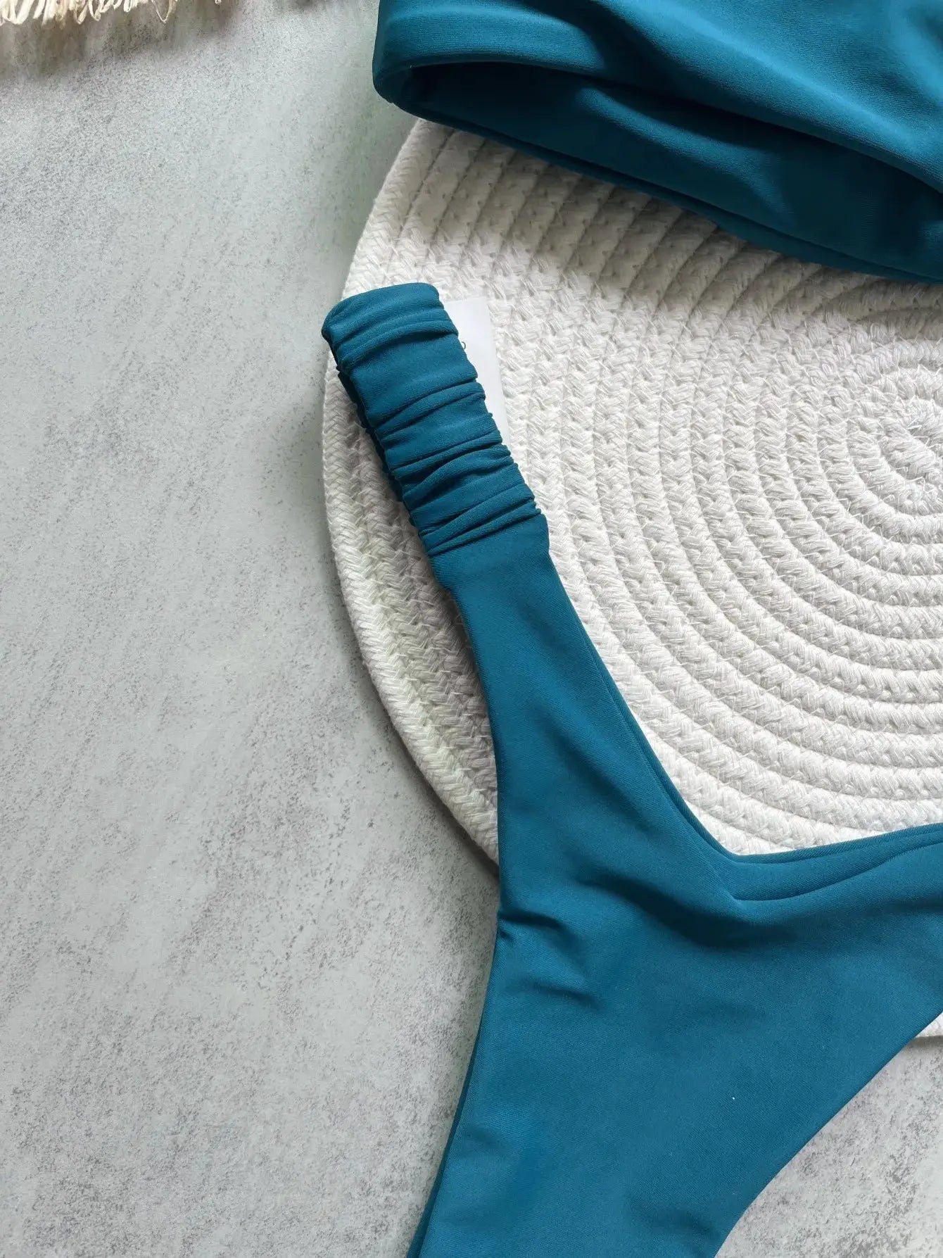 Simples Market teal swimsuit with ruched sleeve on white textured mat