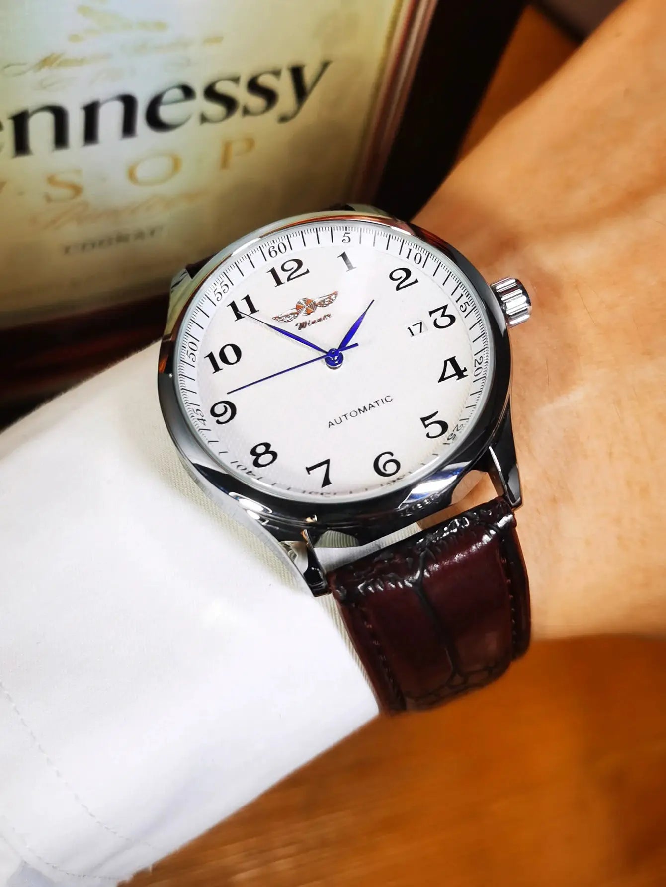 WINNER men's automatic watch with white dial, blue hands, silver case, brown leather strap.