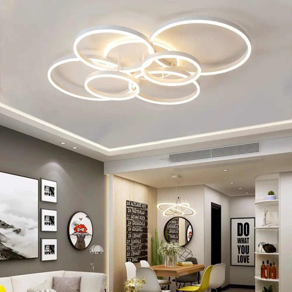 Modern LED ceiling chandelier by Simples Market with interlocking white circular rings, dimmable.