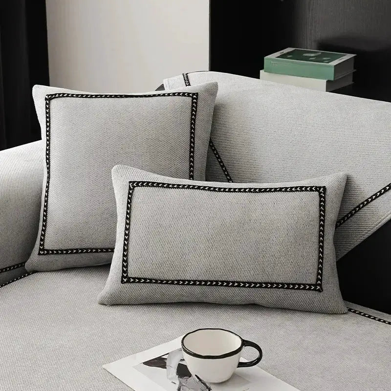 Vintage-style chenille sofa slipcover with two black-trimmed gray cushions on a light gray couch