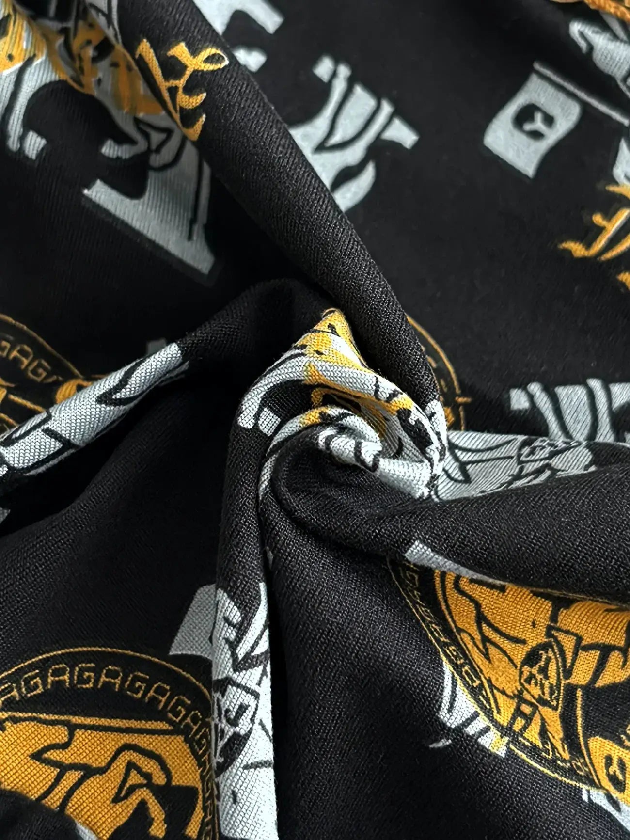 Men's boxer underwear fabric close-up; black with yellow and gray logo prints