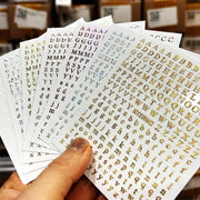 Simples Market 3D alphabet nail stickers in laser silver/gold on 8x10cm sheets; self-adhesive manicure decals