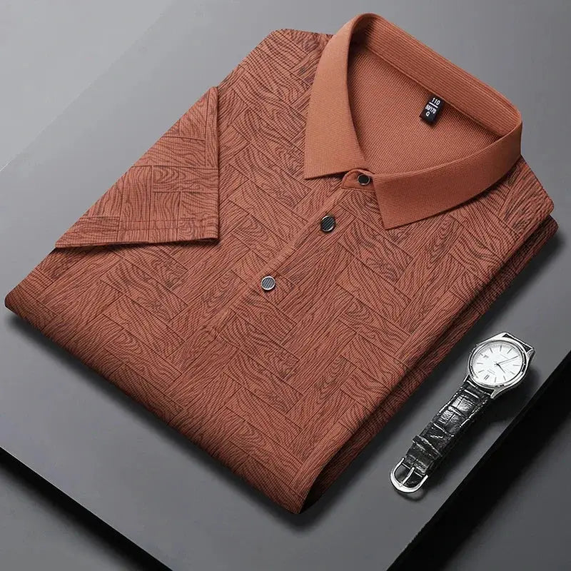 Men's polo shirt by Simples Market in rust-brown geometric print with short sleeves; paired with a wristwatch.