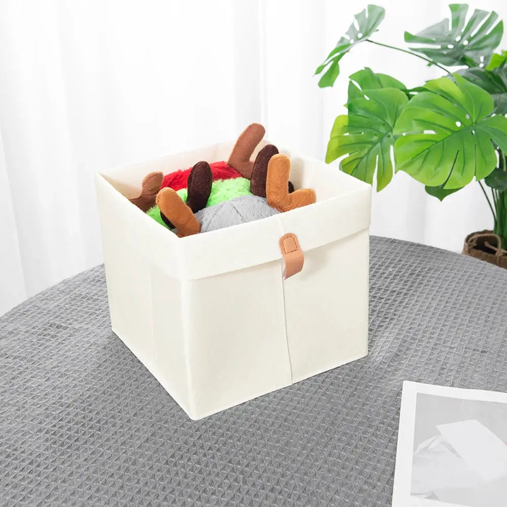 Felt storage basket for clothes and toys, cream color with tan leather strap closure