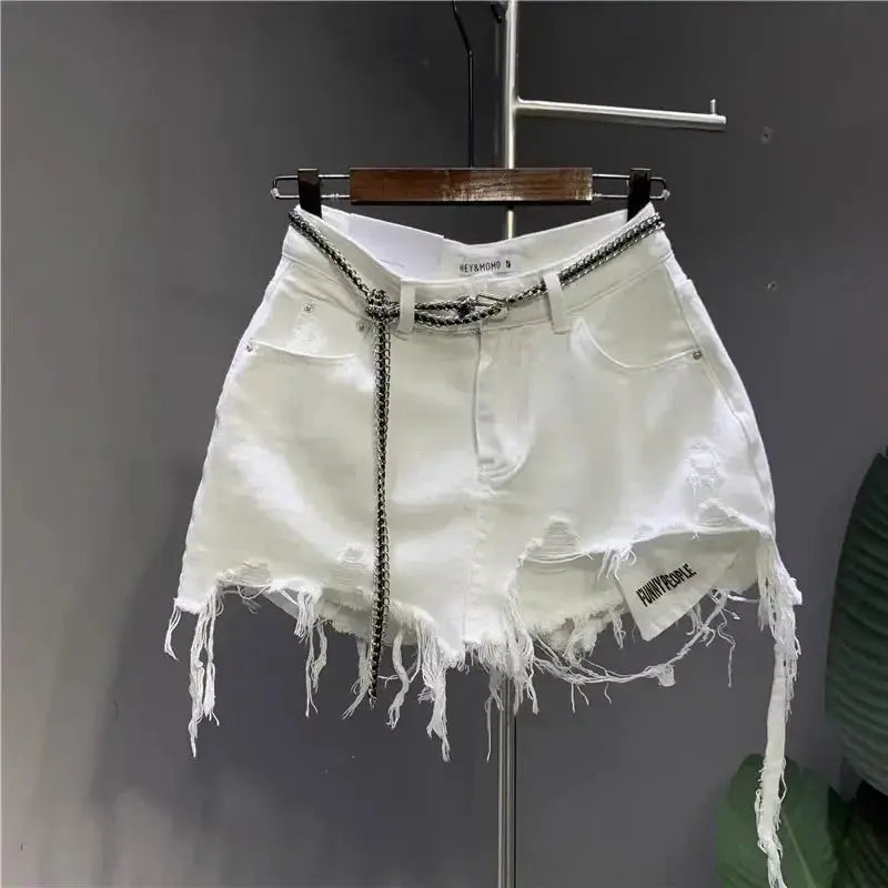 White distressed denim skirt with frayed irregular hem, front pockets, and chain belt by Simples Market