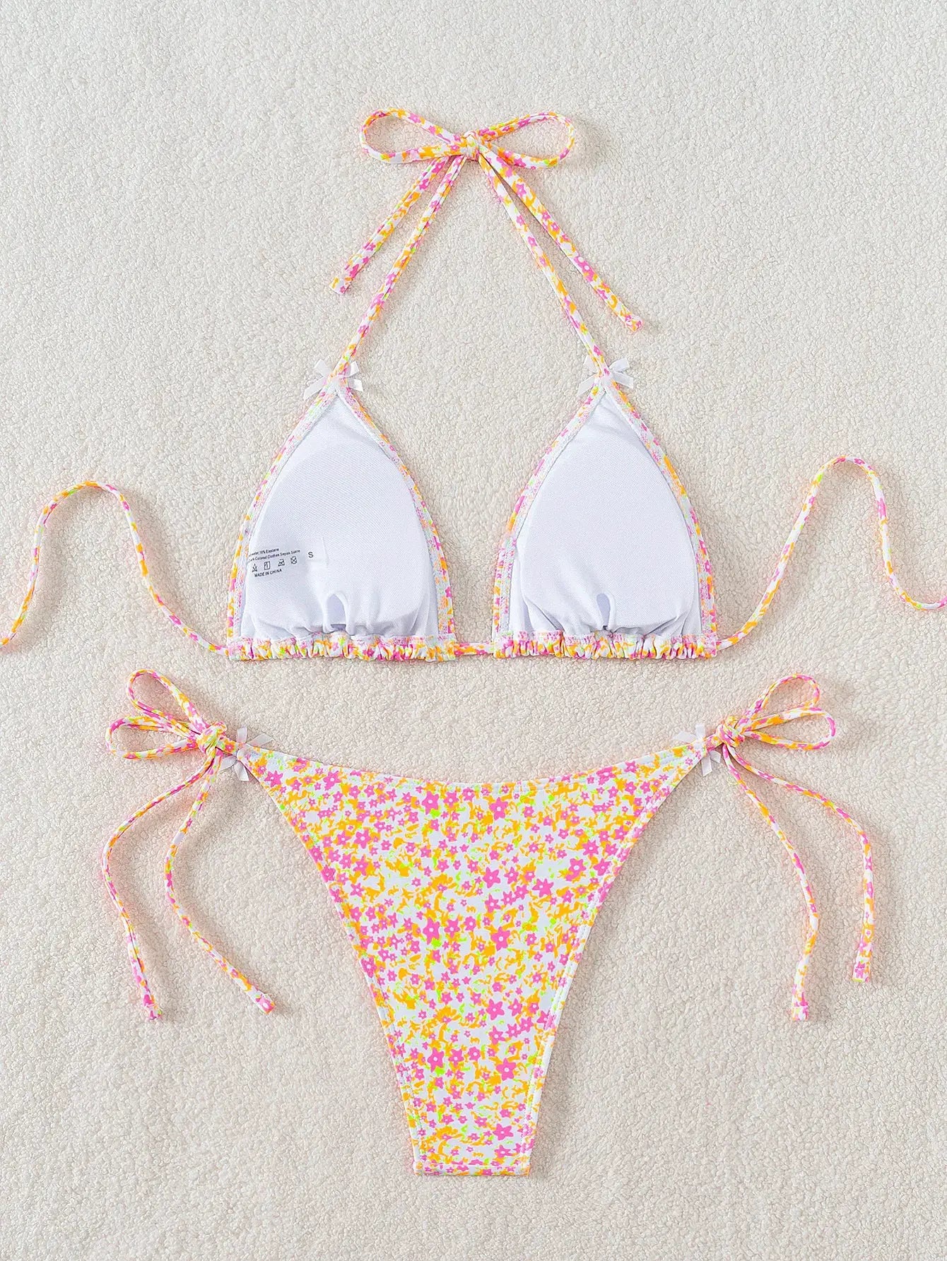 Women's bikini set with white triangle cups, floral trim, and pink-yellow floral tie-side bottoms