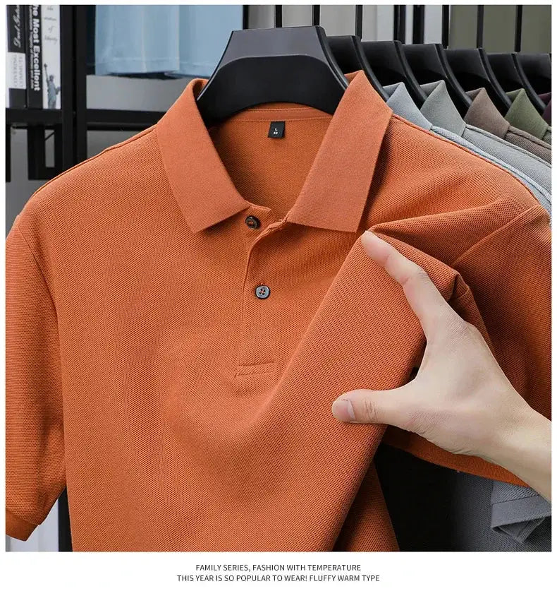Men's 100% cotton polo shirt in orange on hanger with other colors displayed on the rack