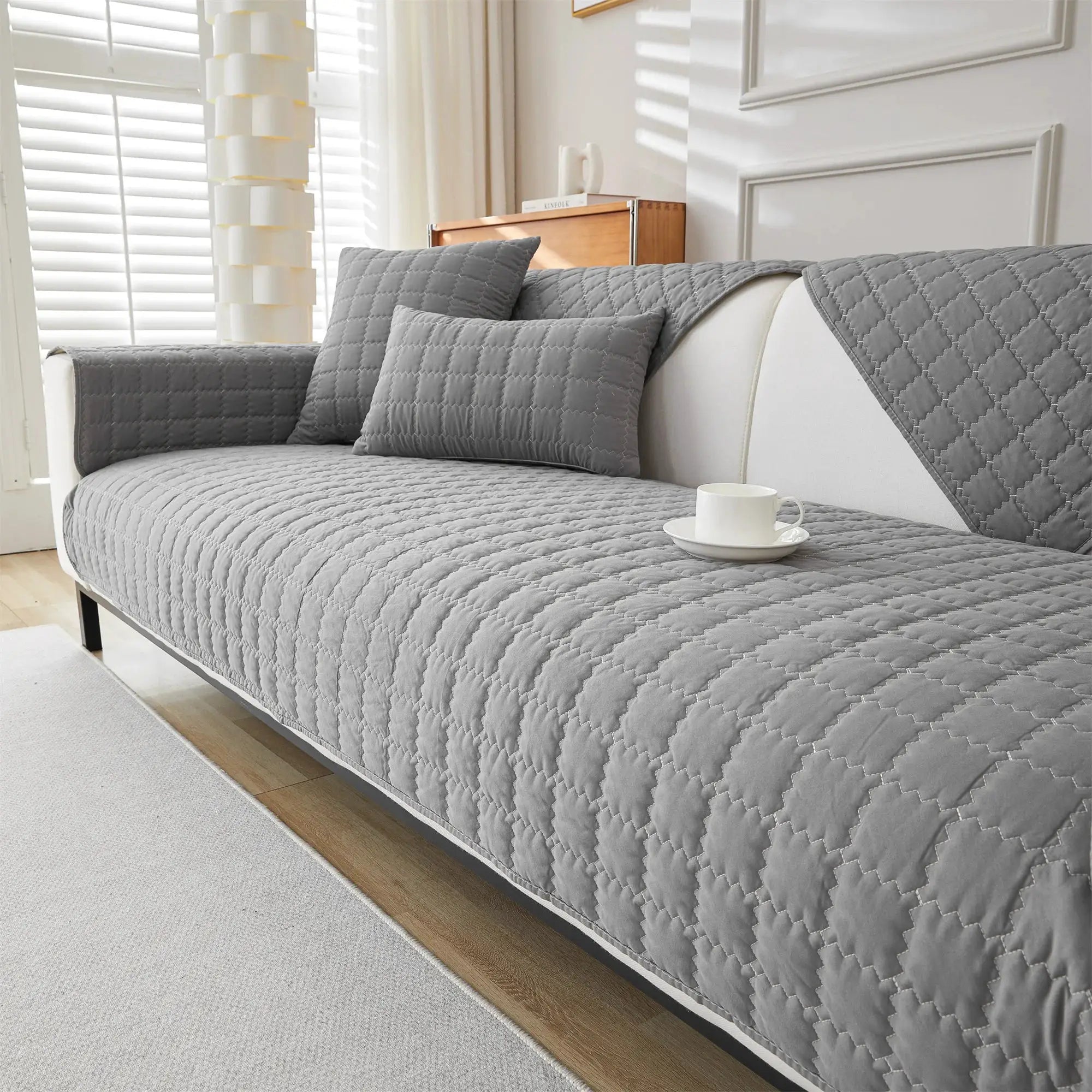 Sofa slipcover gray quilted anti-slip with matching cushions on a living room sofa
