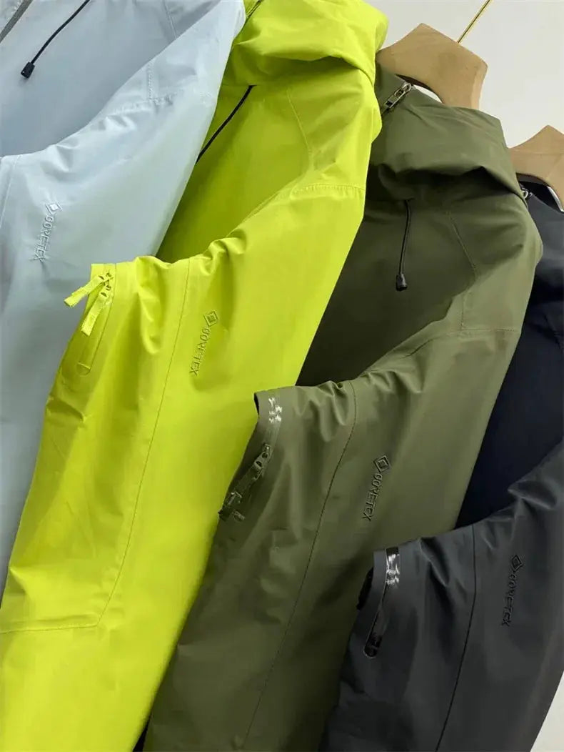 Four GORE-TEX soft-shell outdoor jackets on wooden hangers in light blue, neon yellow, olive green and black.
