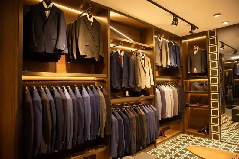 Men's formalwear display with navy and charcoal suits on wooden racks in a boutique