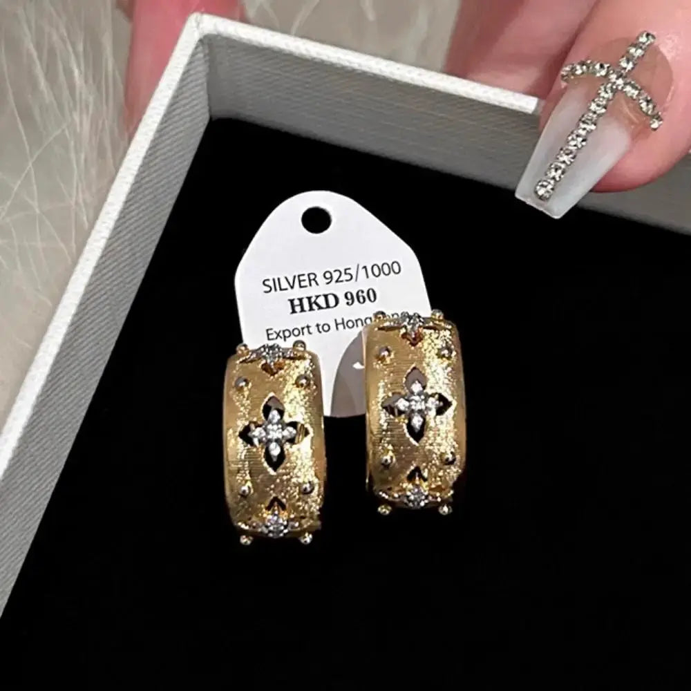 Gold-tone hollow flower stud earrings with zircon inlays, a pair