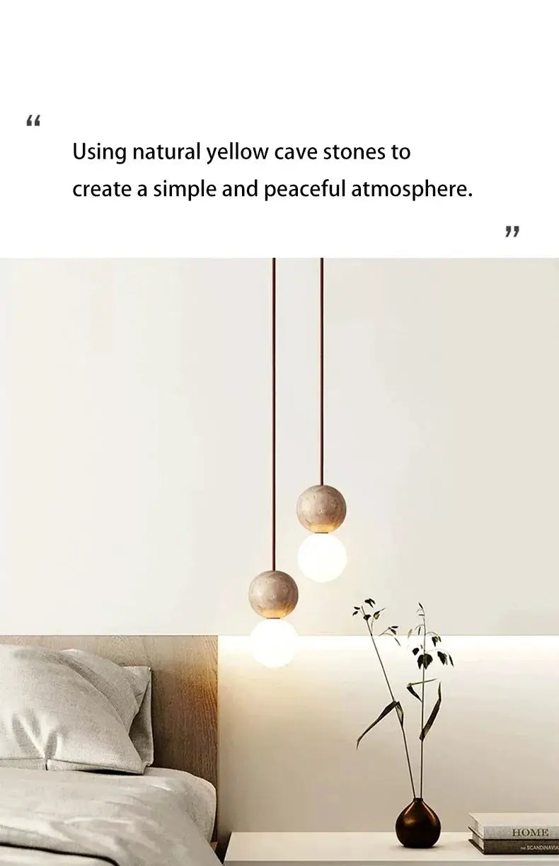 Led pendant lights with cream stone spheres on cords; two bedside lamps over a bed.
