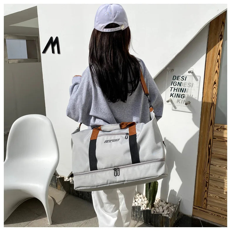 Beichard large-capacity gray travel gym bag with brown top handles and black straps, carried by a person in a gray top.