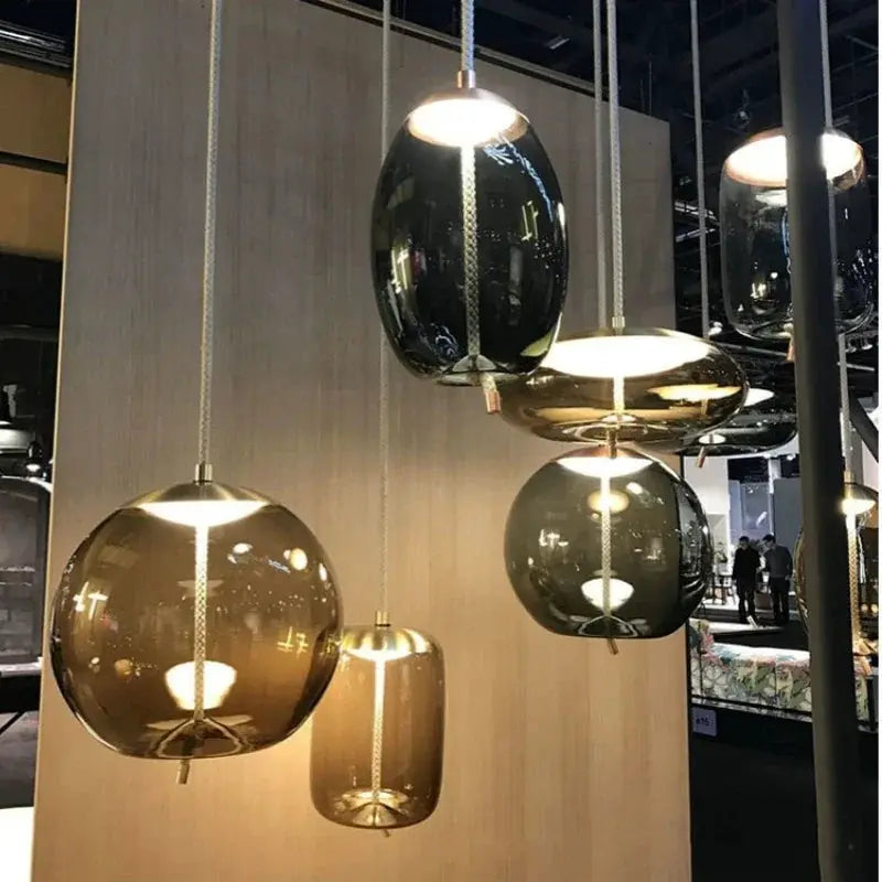 Minimalist glass pendant lamps; multiple hanging amber and smoky gray fixtures with hemp rope suspensions.