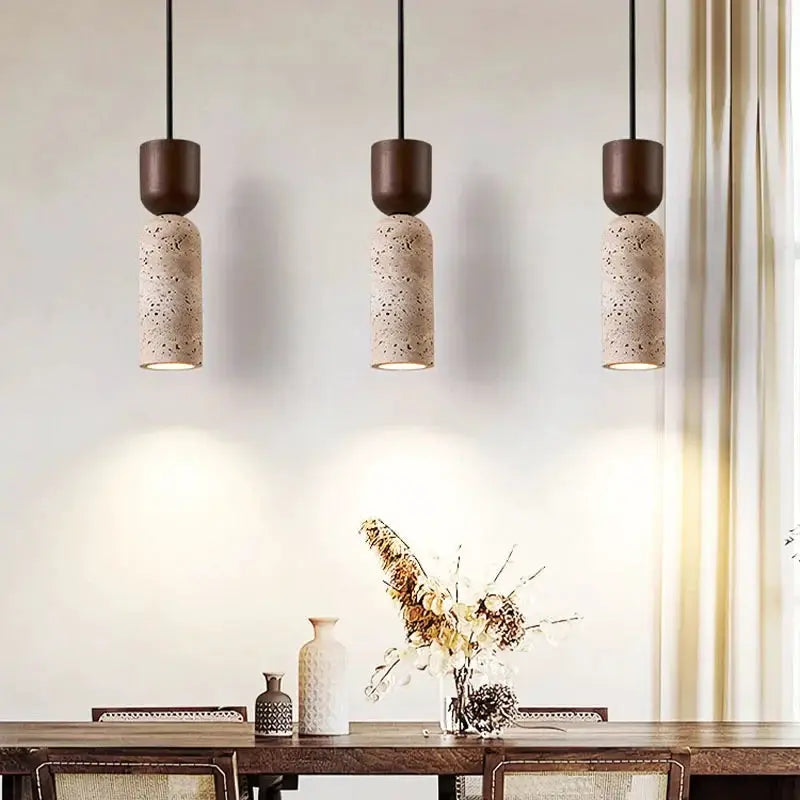 Three beige speckled ceramic pendant lights with dark brown tops hang over a wooden dining table.