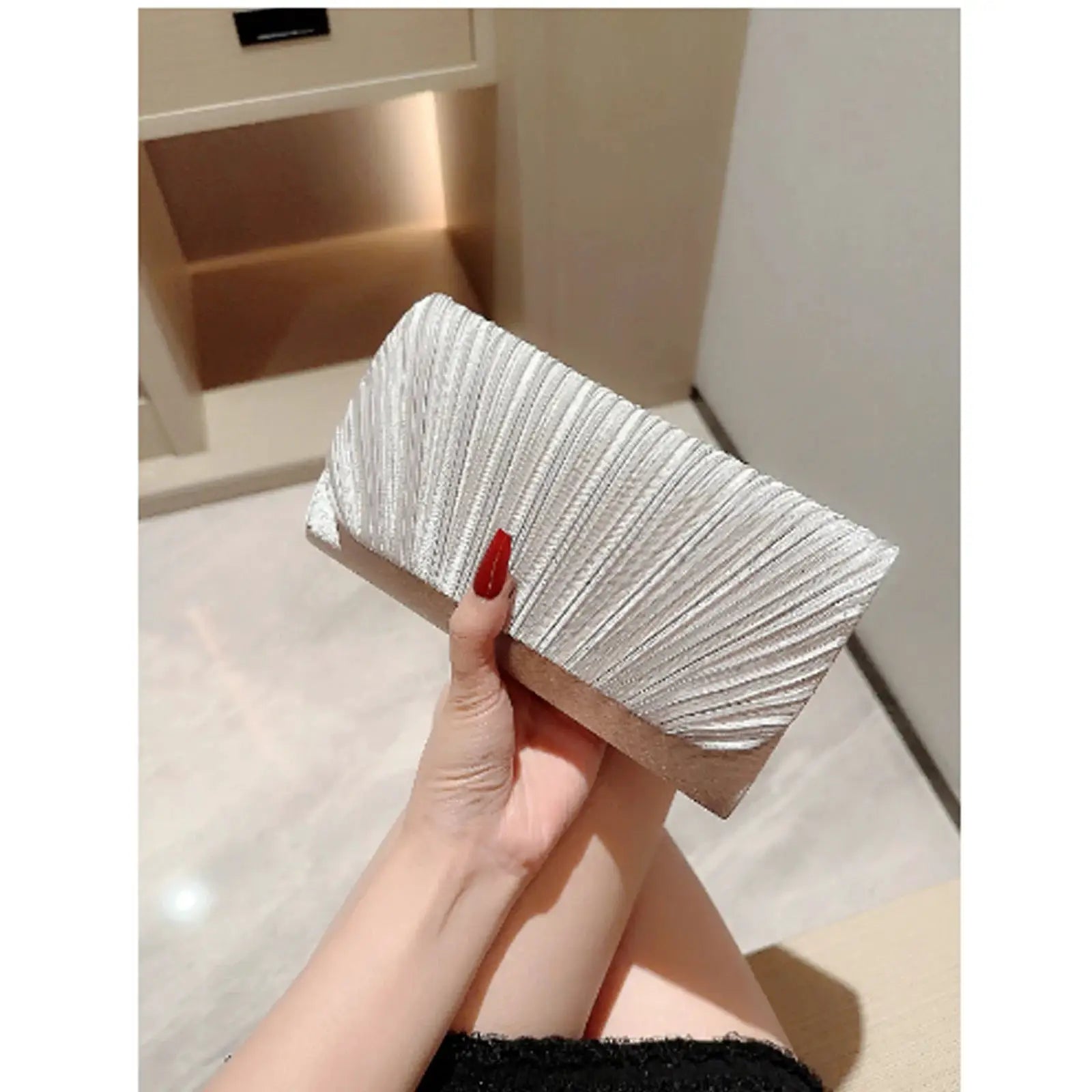 Silver textured metallic pleated evening clutch bag held in hand