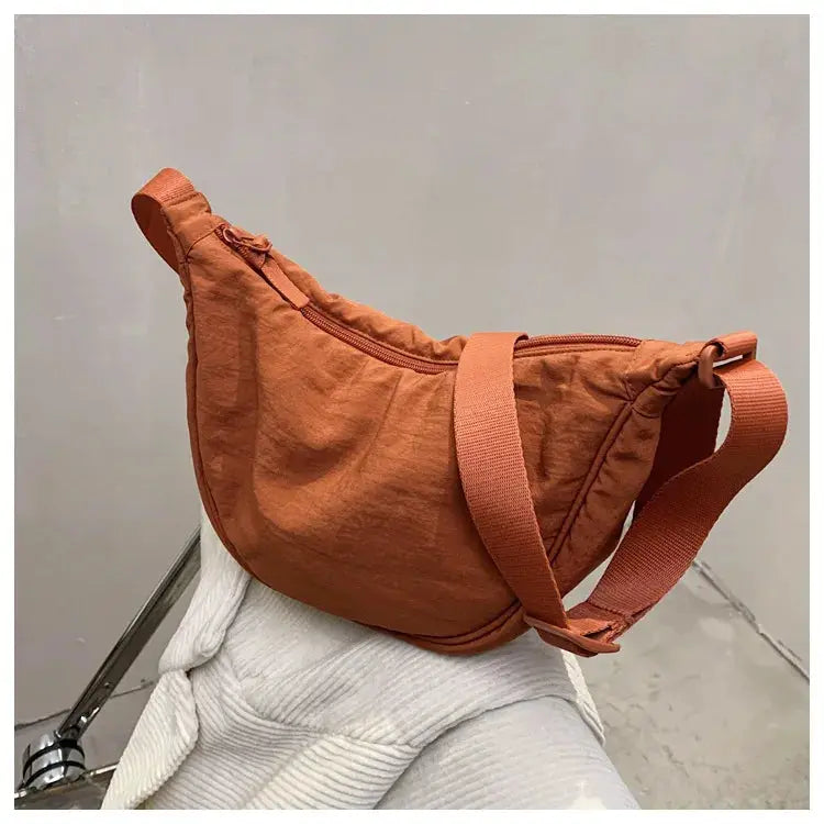 Casual nylon hobo crossbody bag in rust orange with wide adjustable strap and zipper.