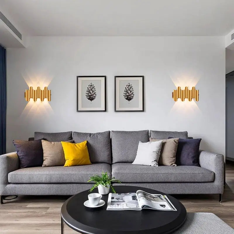 Pair of aluminum golden LED wall light sconces on a white living room wall, illuminated.