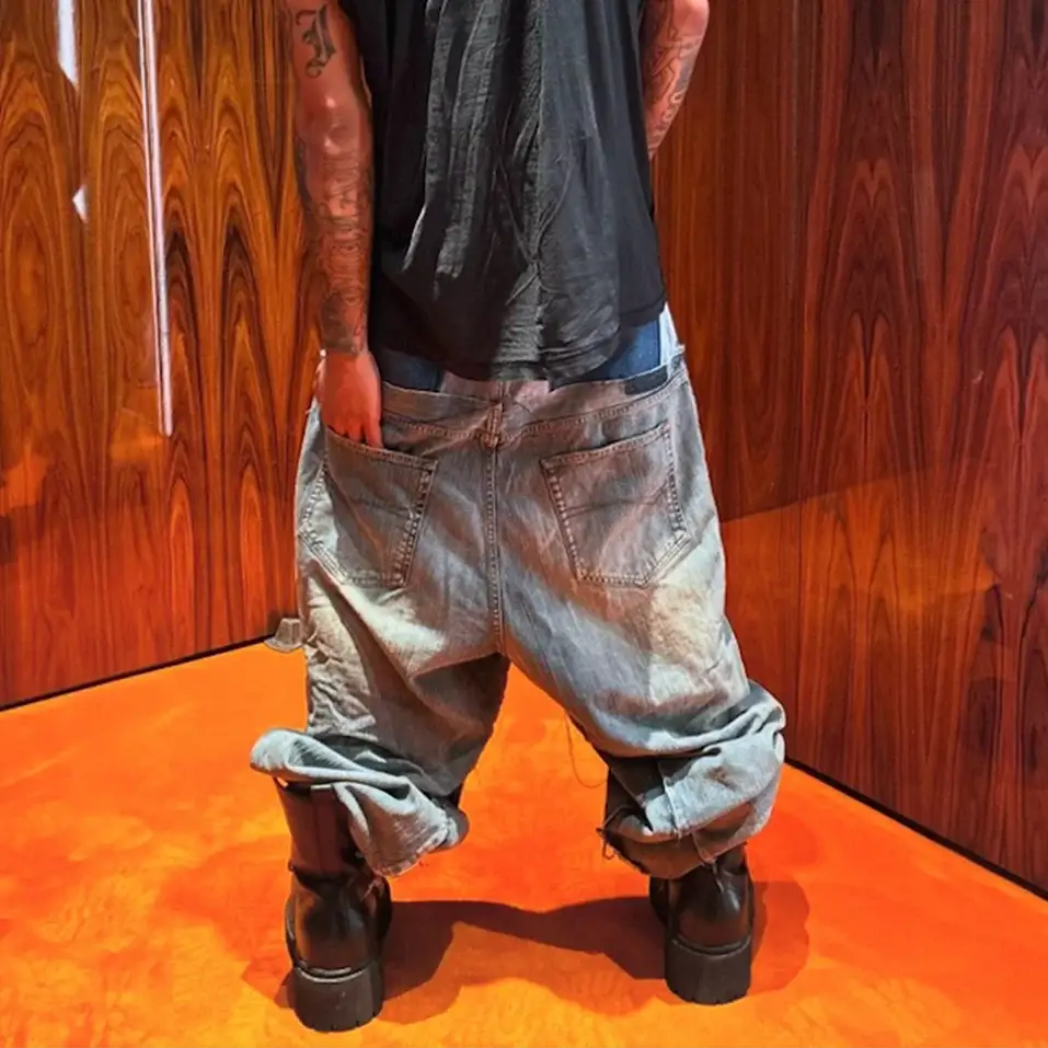 Baggy denim jeans with light wash and rolled cuffs, back pockets visible on a model wearing a black top