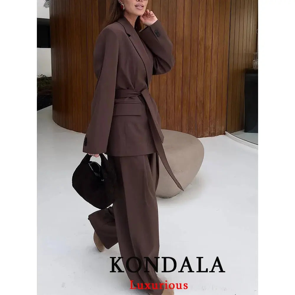 KONDALA brown women's blazer suit with a sash belt and matching wide-leg pants, carrying a black handbag