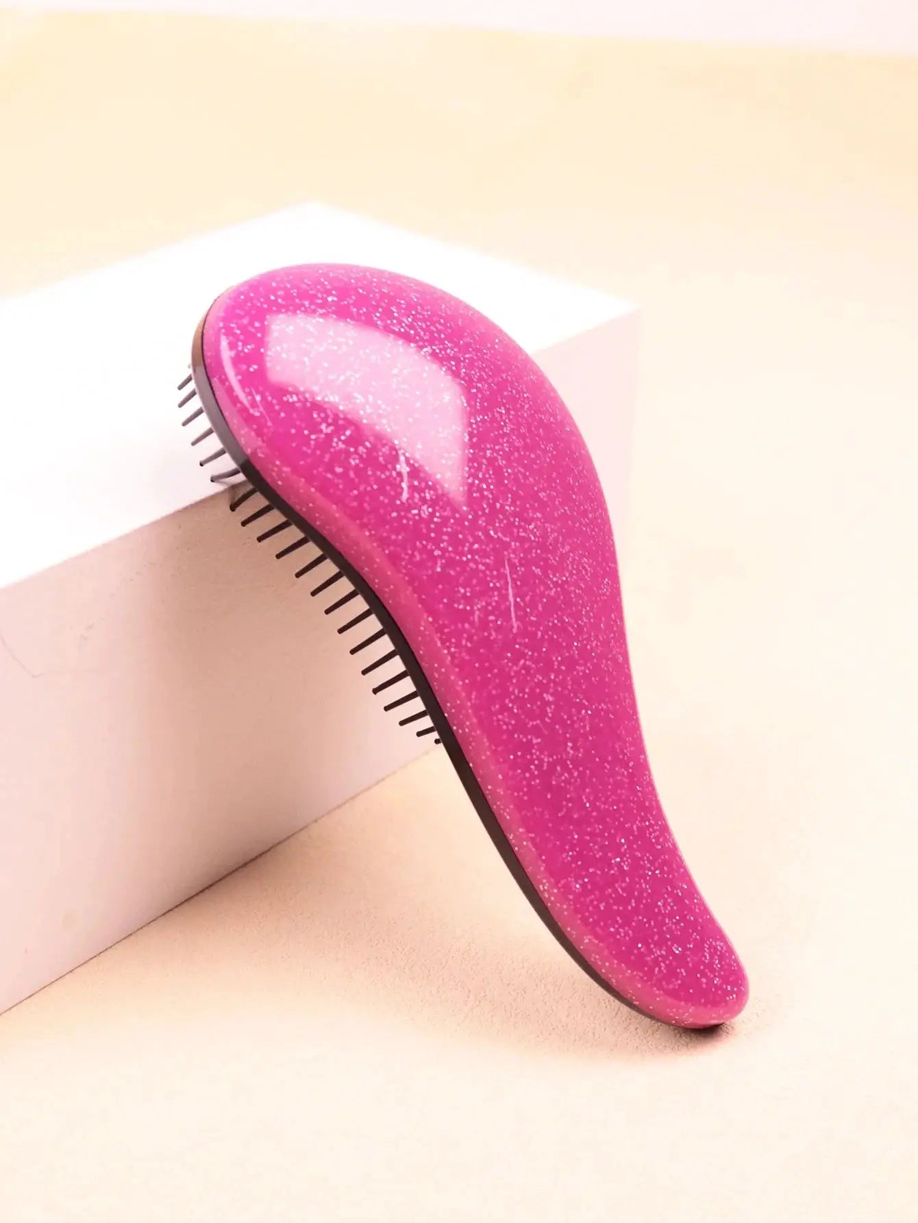 Smoothing brush for natural, wet and dry hair with curved pink handle and black bristles.