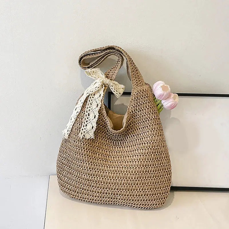 Natural brown rattan shoulder bag with a white lace scarf tied to the strap; large casual beach tote