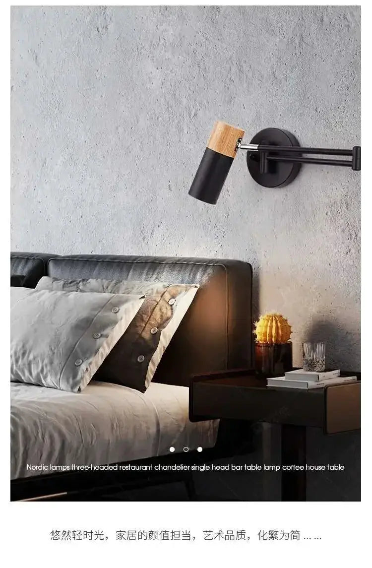 Wall-mounted reading lamp with black metal arm and cylindrical shade with wood top, over a bedside table.