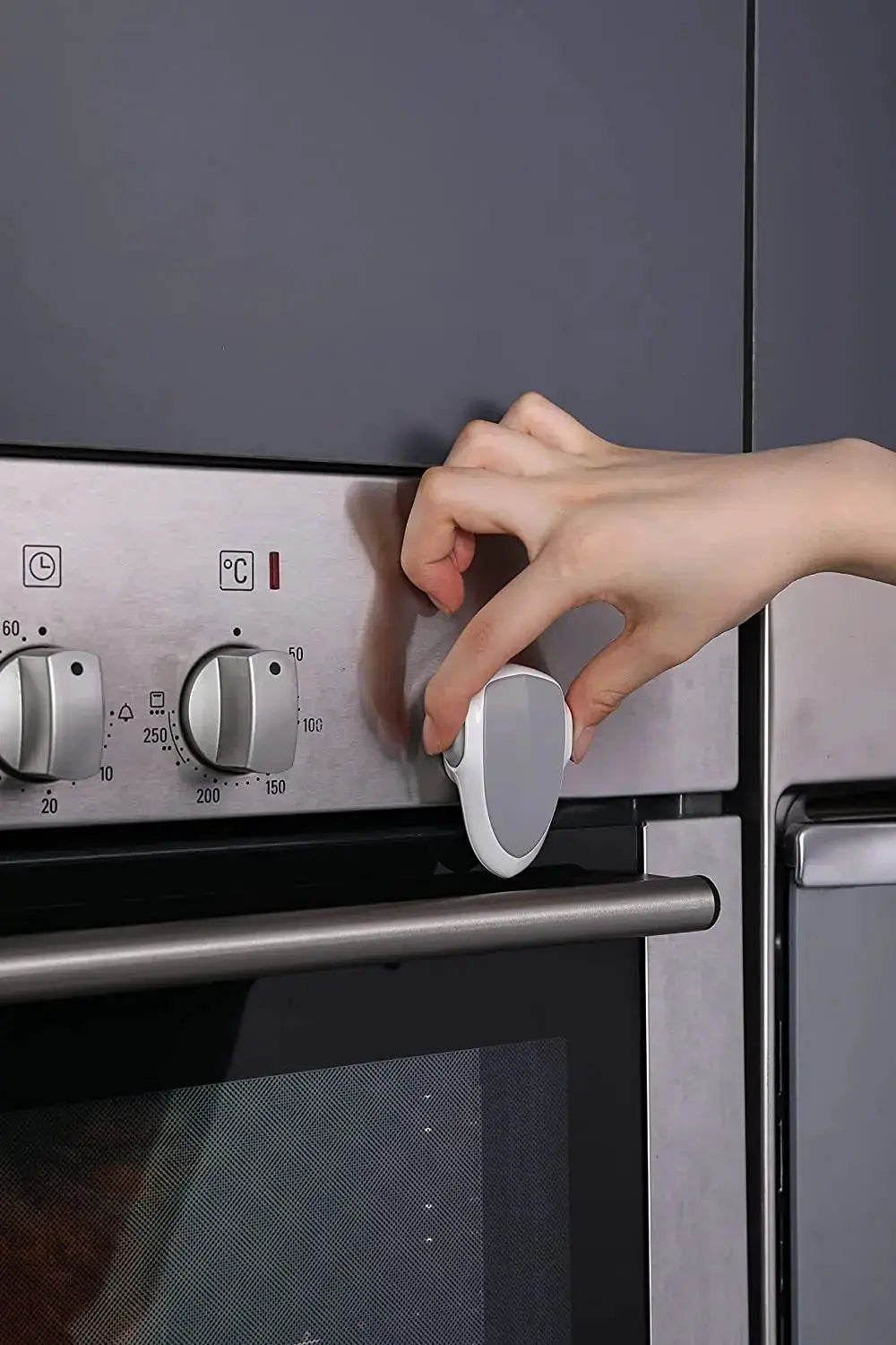 Baby oven door lock by Simples Market, white and gray plastic safety lock on a stainless steel oven