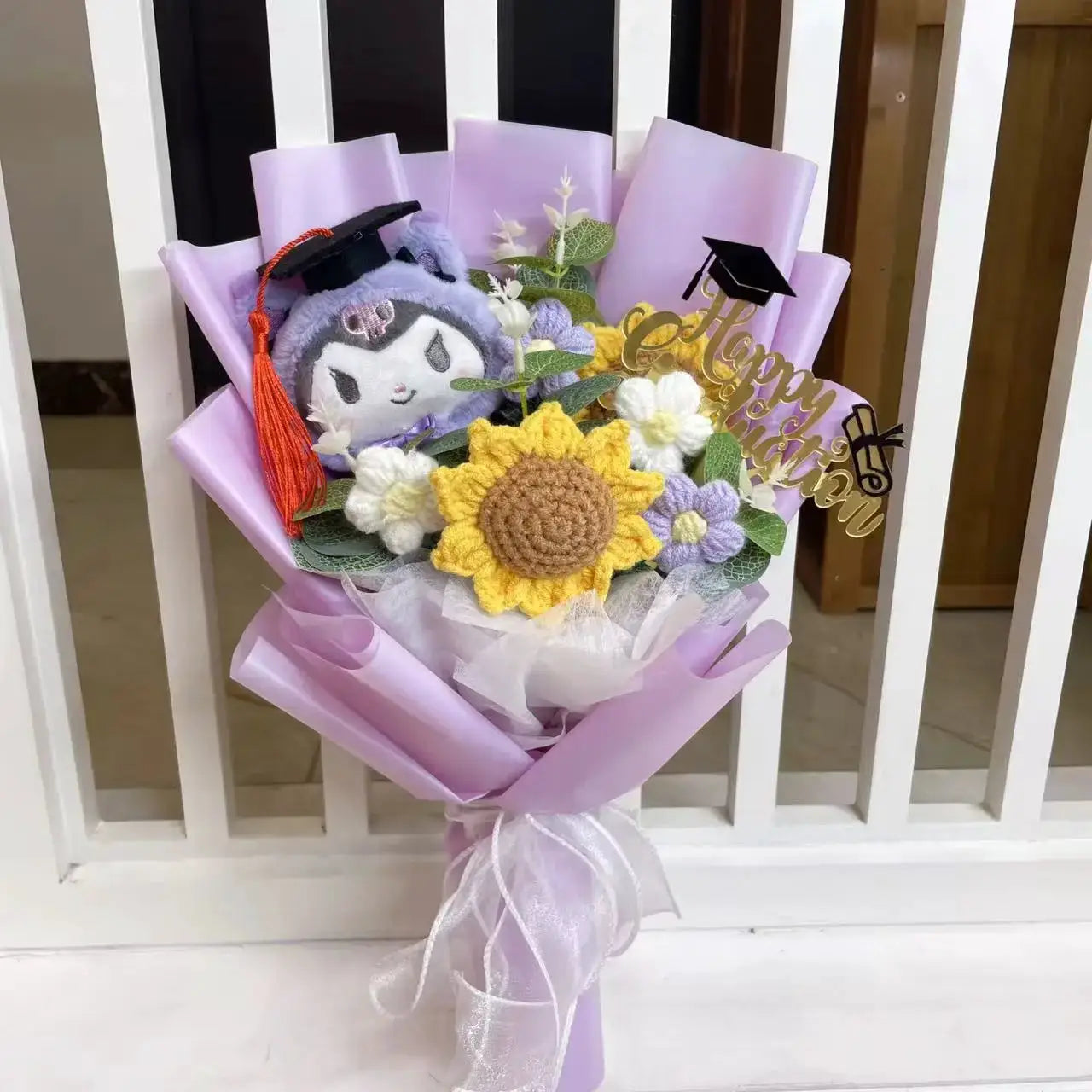 Stuffed Plants Bouquet by Simples Market; lavender wrap with crocheted sunflowers, white blooms, and a plush wearing a graduation cap