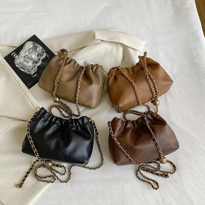 Four leather-look chain shoulder bags with gold-tone straps in black and brown tones