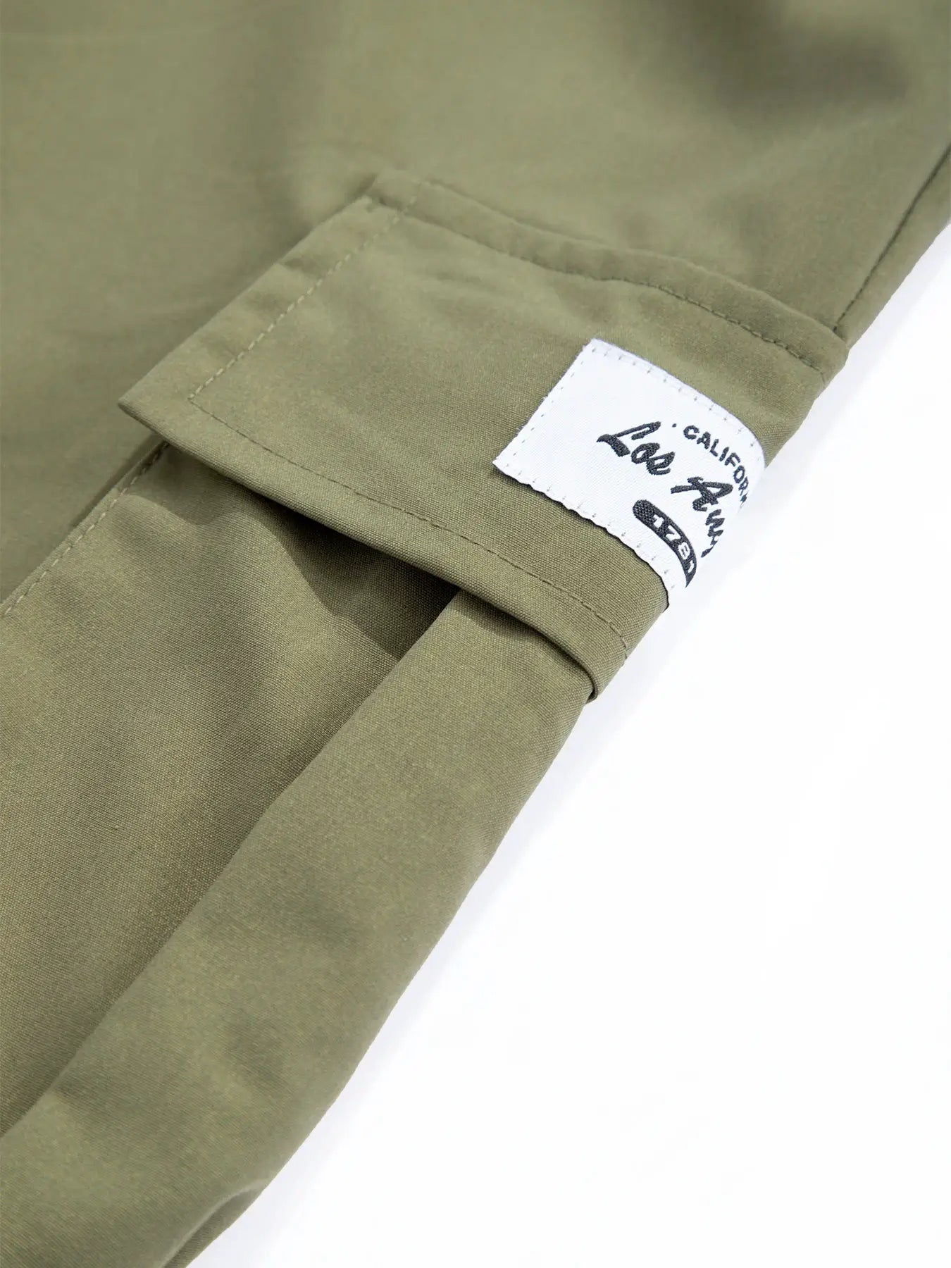 Men's olive cargo pants with loose straight fit and multi-pocket design; white label patch on the cuff.
