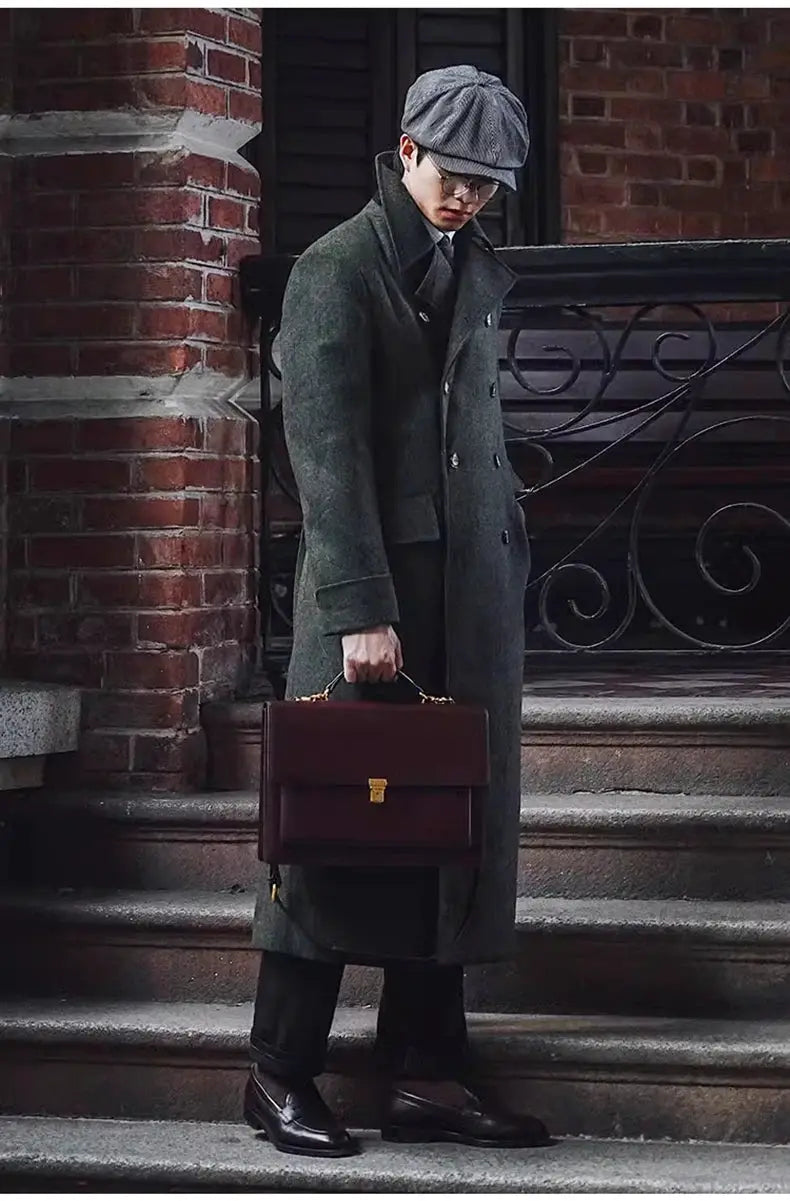 Men's green wool-blend double-breasted overcoat shown with a brown briefcase on stone steps.