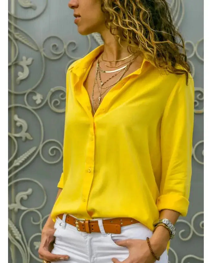 Yellow women's blouse with polo collar and button-up front, long sleeves rolled, paired with white pants.