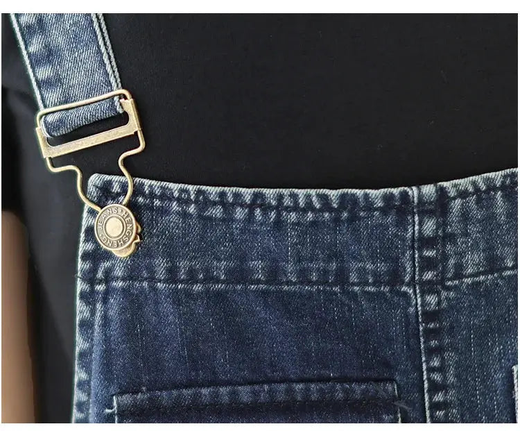 Women's blue denim overalls with suspender straps, metal buckle and front pocket detail