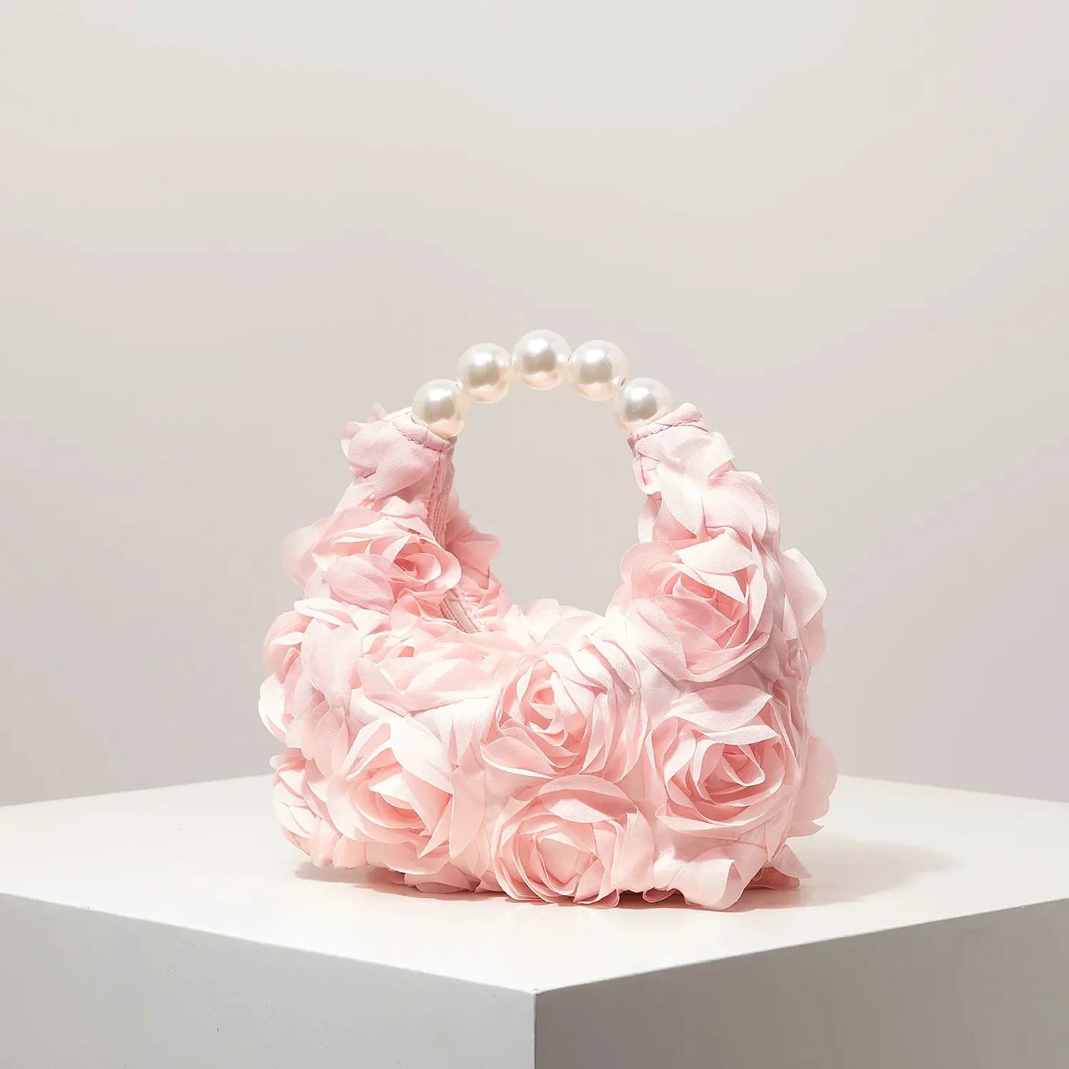 Pink floral handbag with pearl-bead handle and ruffled petals by Simples Market