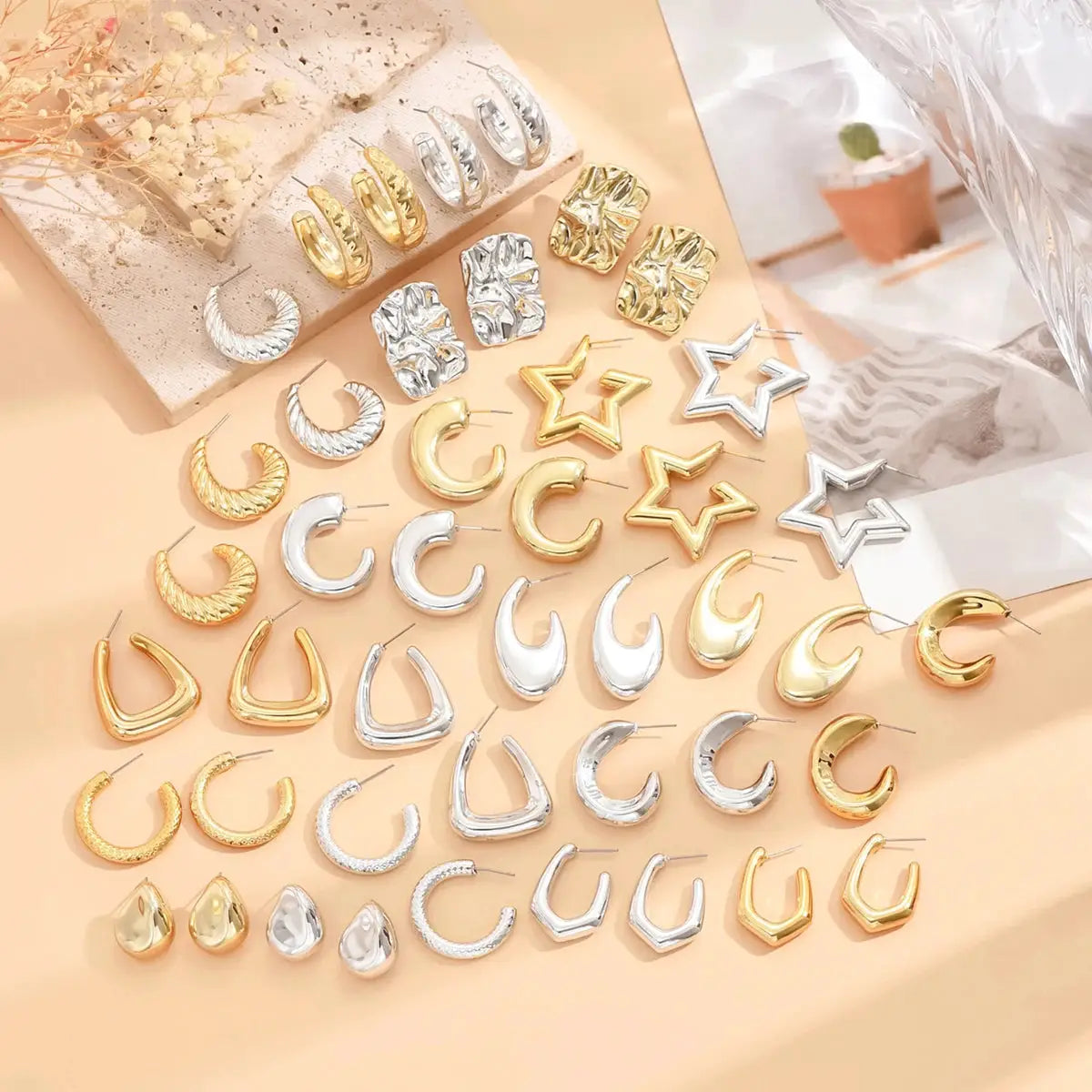 Geometric irregular stud earrings in gold and silver tones, featuring stars, crescents, squares and hoops