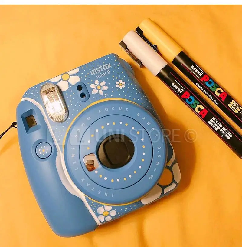 Uni Posca paint marker pens set PC-1M PC-3M PC-5M beside blue Instax Mini 9 camera