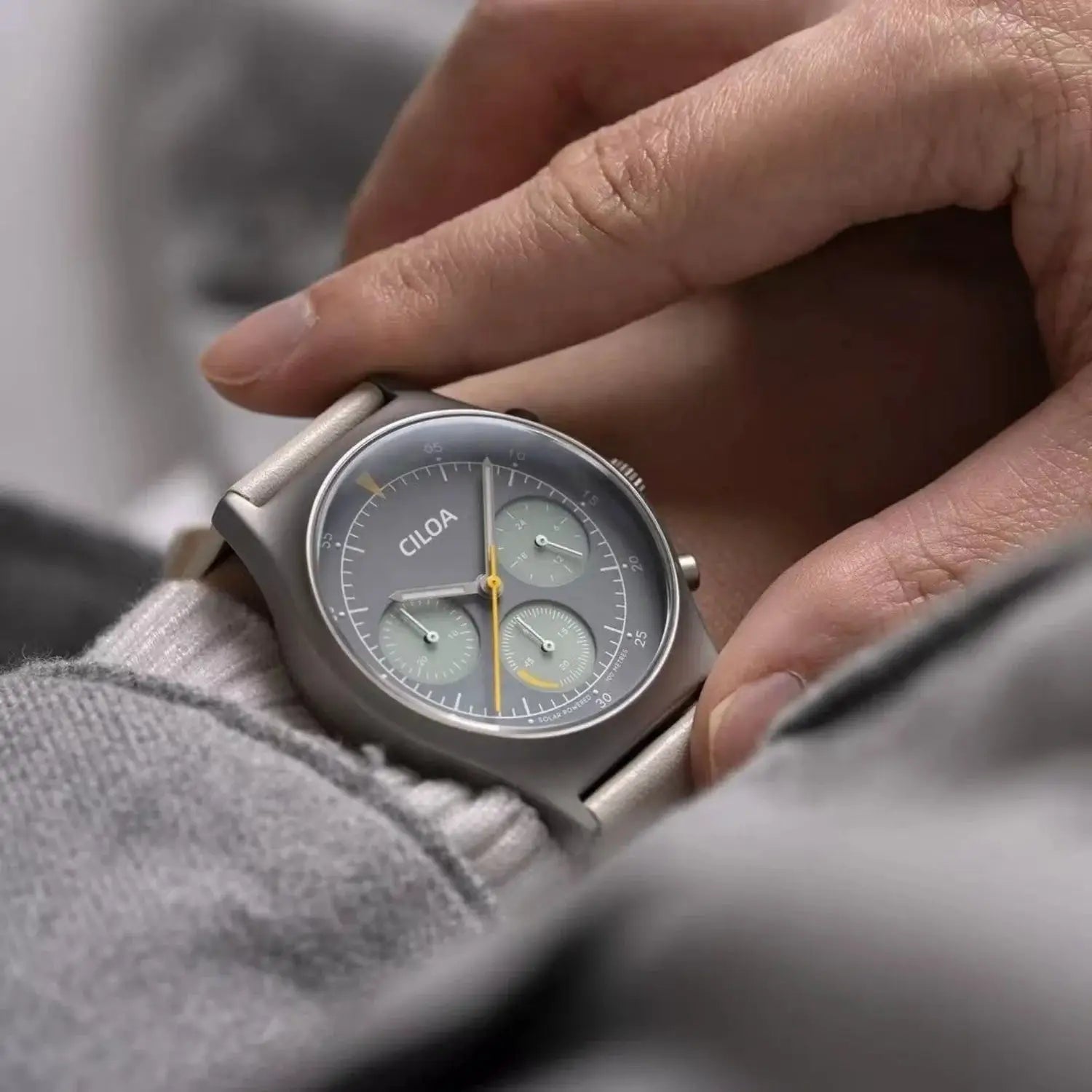 CILOA round gray men's watch with large dial and multiple subdials; matte metal case and band.