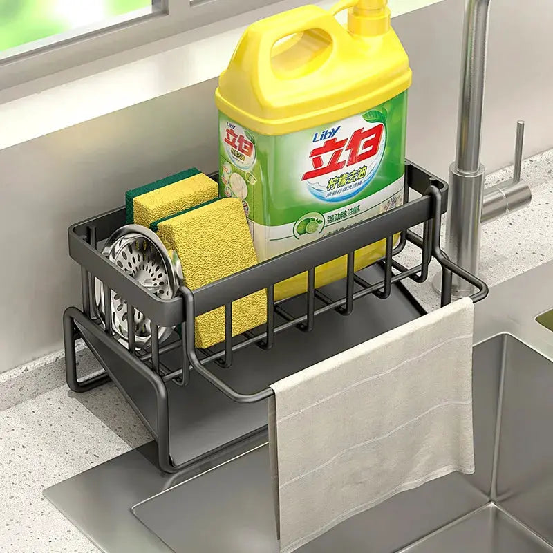 Black metal kitchen sink drain rack with towel bar, holding two yellow sponges and a dish soap bottle.