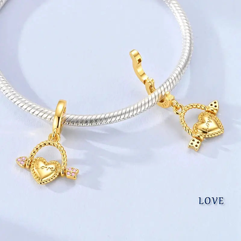 Heart charm pendants, gold-tone with pink stones, for bracelets; set of 2 on a silver bracelet.
