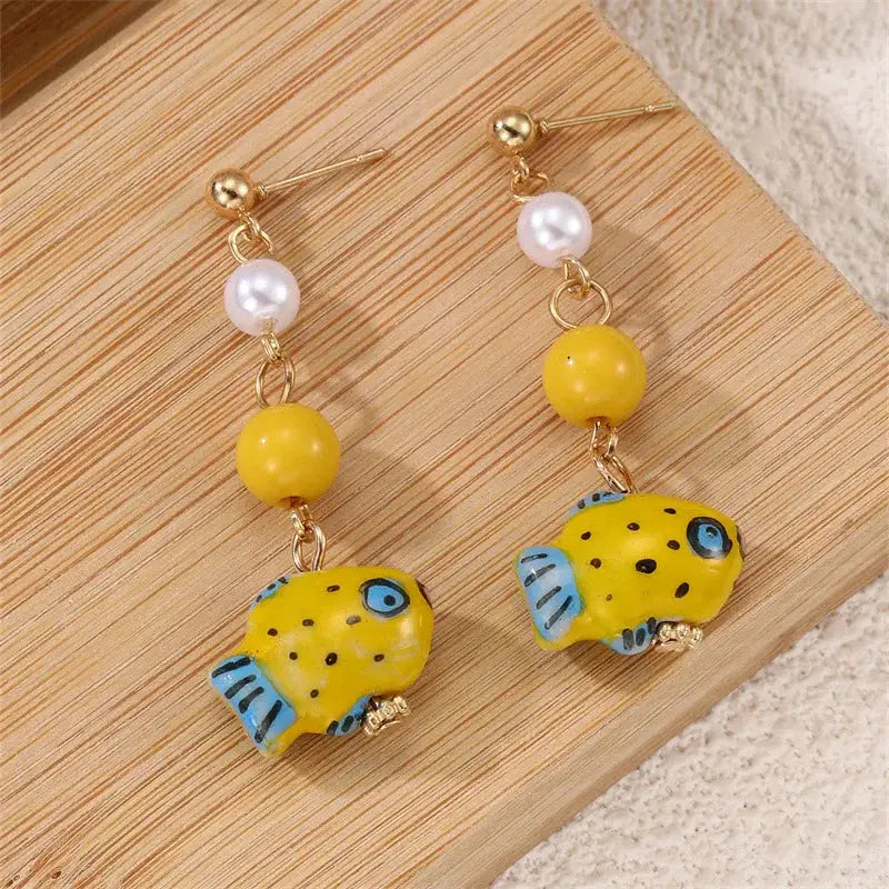 Pair of yellow glass octopus drop earrings with white pearl beads and blue fin accents
