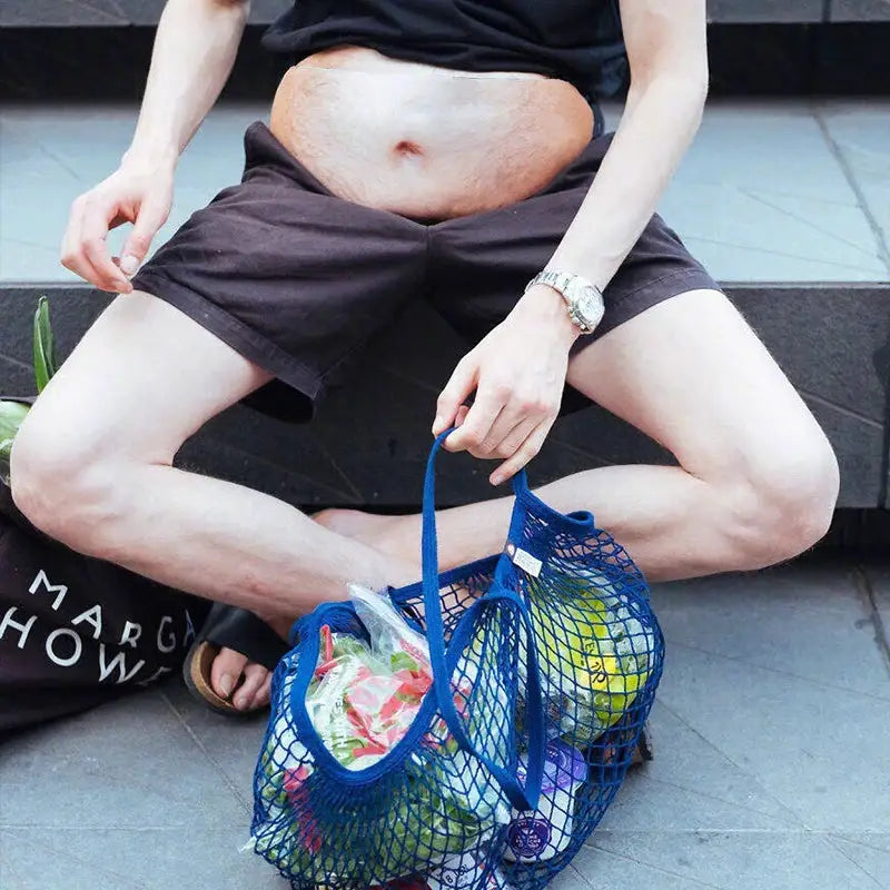 Blue mesh fanny pack waist bag with groceries inside, held by man