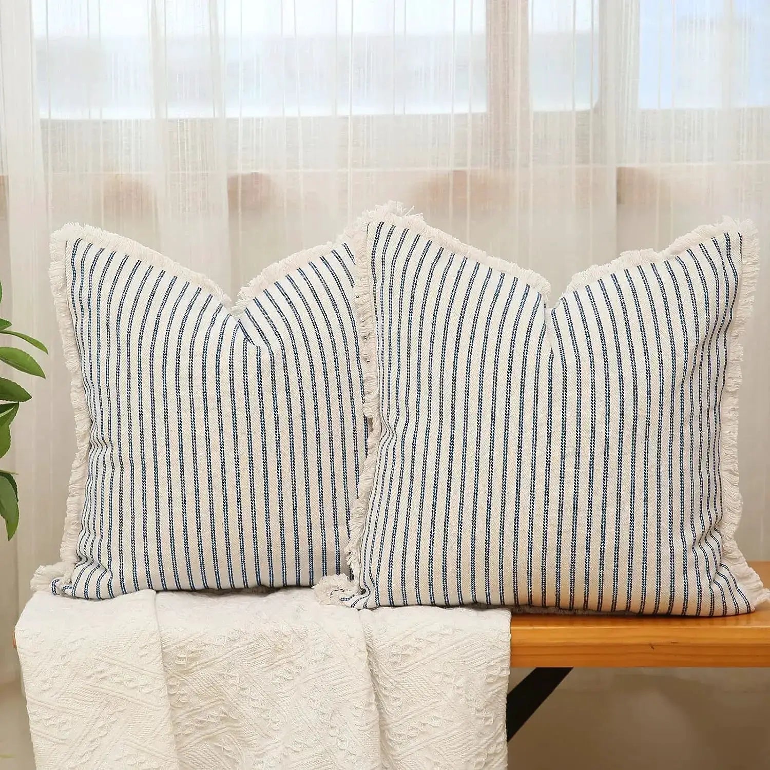 Two square striped cushion covers, white with blue stripes and fringed edges.