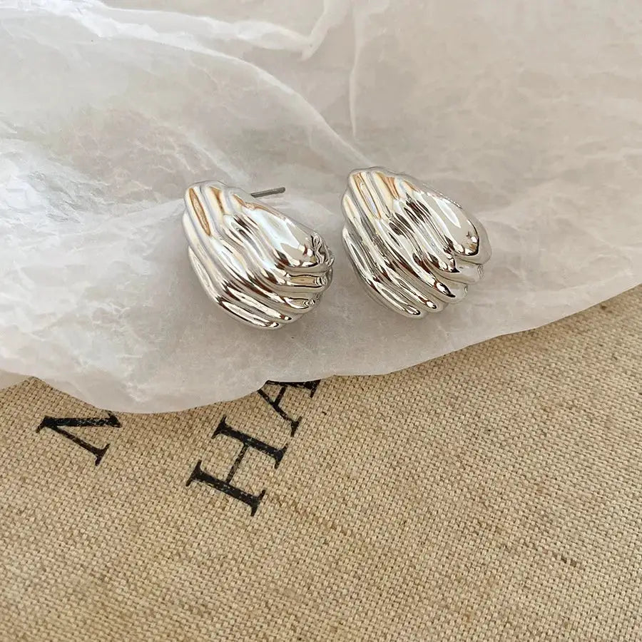 Unisex irregular oval pleated acrylic stud earrings in gold and silver tones by Simples Market