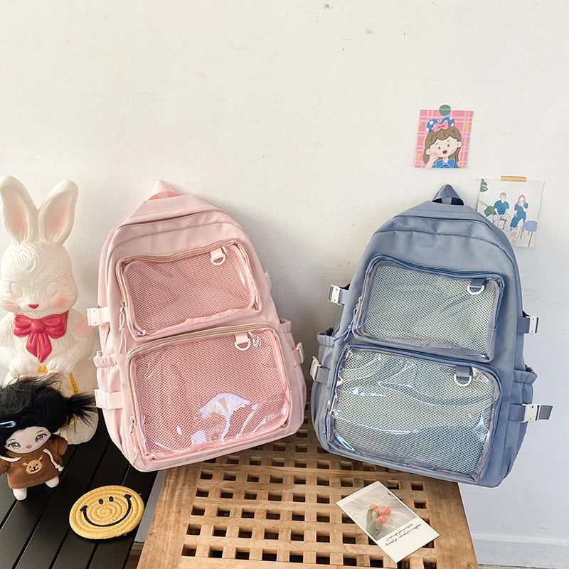 Two Japanese-style transparent ita backpacks in pink and blue with mesh front pockets; large-capacity school bags.