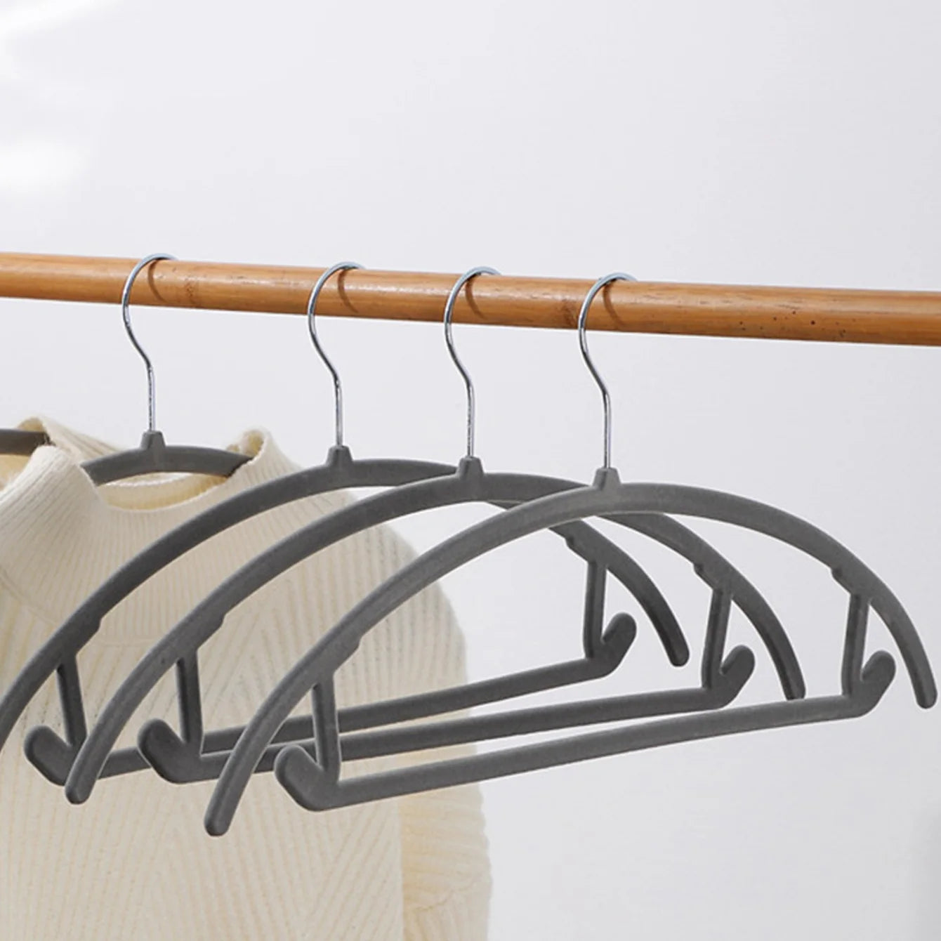 Simples Market velvet plastic clothes hangers, grey with metal hooks; four-pack displayed on a wooden rod